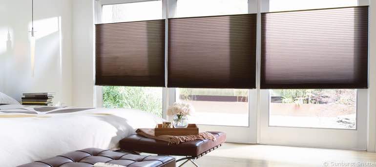 Modern Riverside bedroom with tall windows and brown cellular shades.