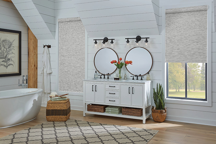 Slim-profile roller shades easily fit shallow windows in your Riverside home. Gray patterned roller shades on bathroom windows