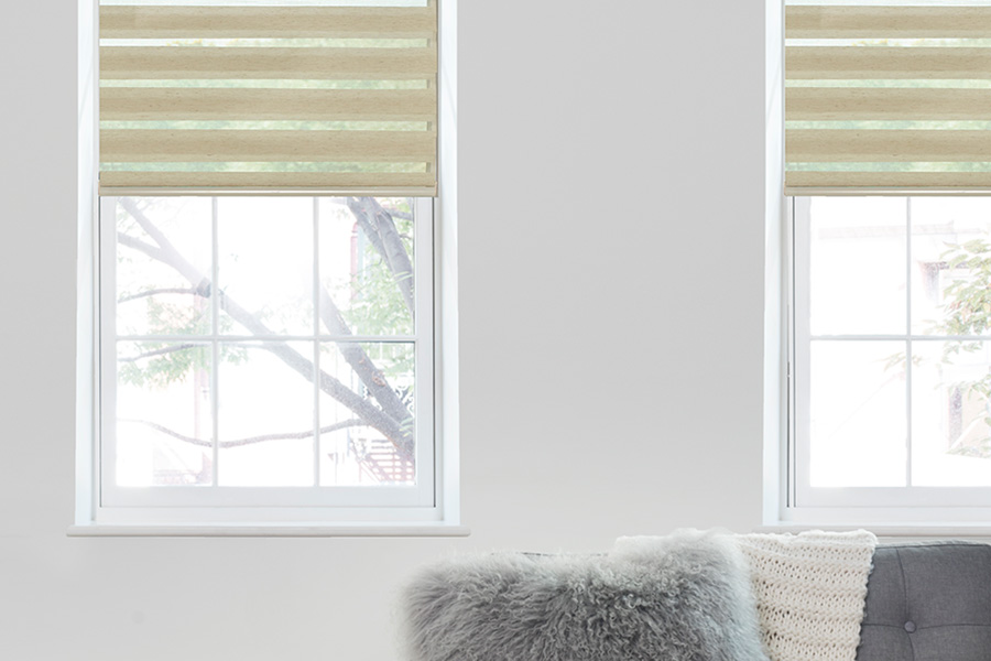 Choose motorized window shades in when you want cordless window treatments for pets and kids. Beige transitional shades on windows in a neutral living room
