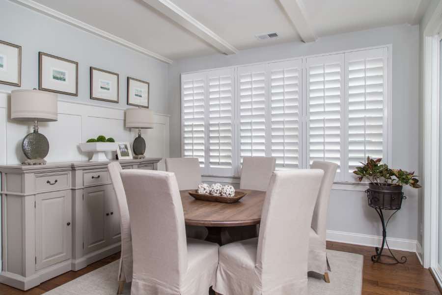 White Polywood shutters are easy to clean, so they always look pristine. Polywood shutters on a large window in a neutral-colored dining room