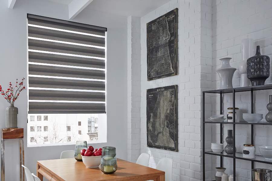 The solid and sheer bands of zebra shades are perfect for managing light in any space, including this cozy dining spot. Zebra shade controlling light in a cozy dining area