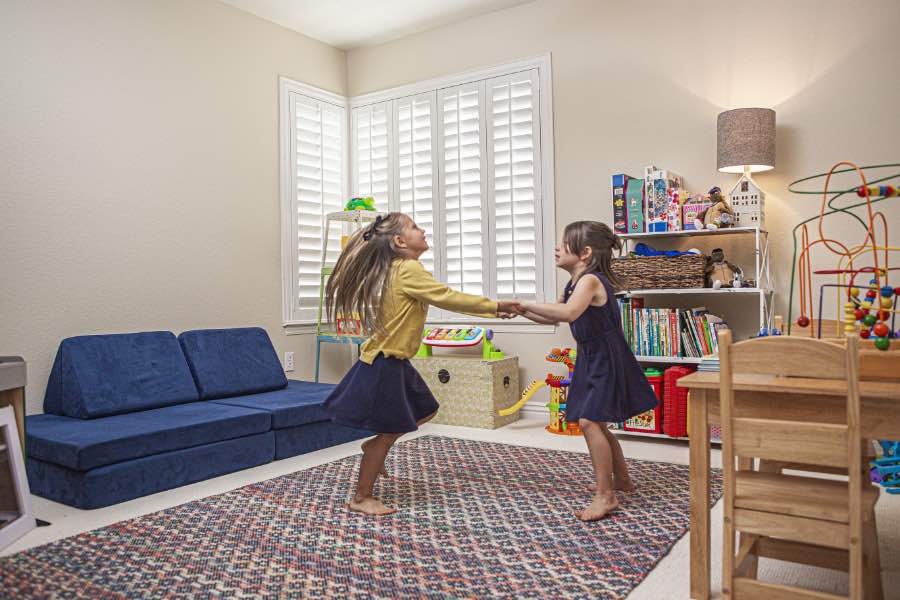 Choose Polywood shutters for durable, kid-friendly great room window treatments in Riverside. Polywood shutters on multiple windows in a sitting area