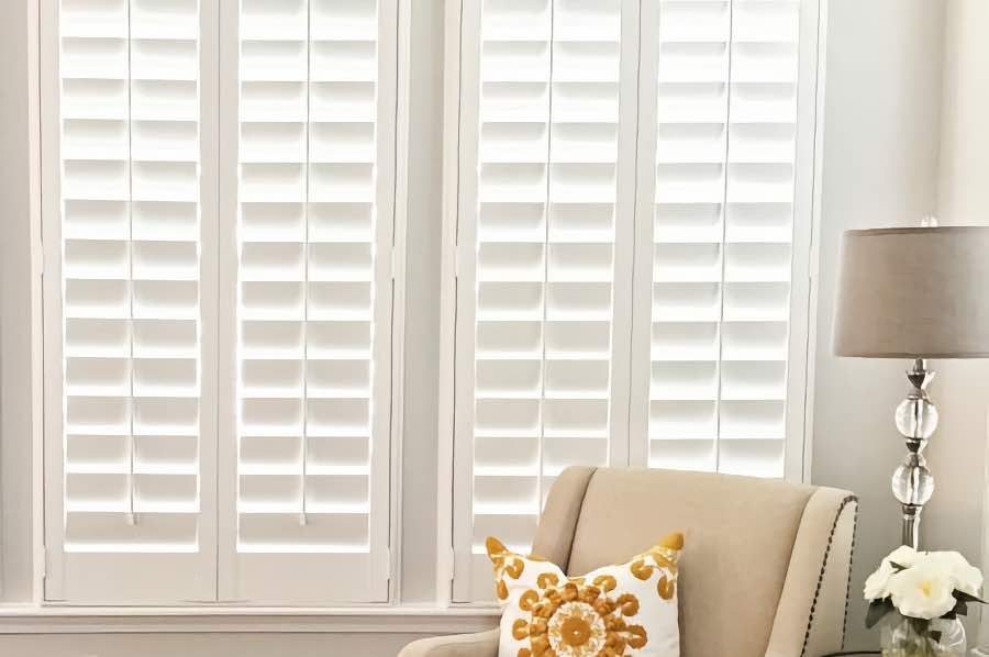 Apply for an energy tax credit when you install beautiful Polywood shutters this year. Photo credit: The Mommy Nichols An armchair next to white Polywood interior shutters on a living room window