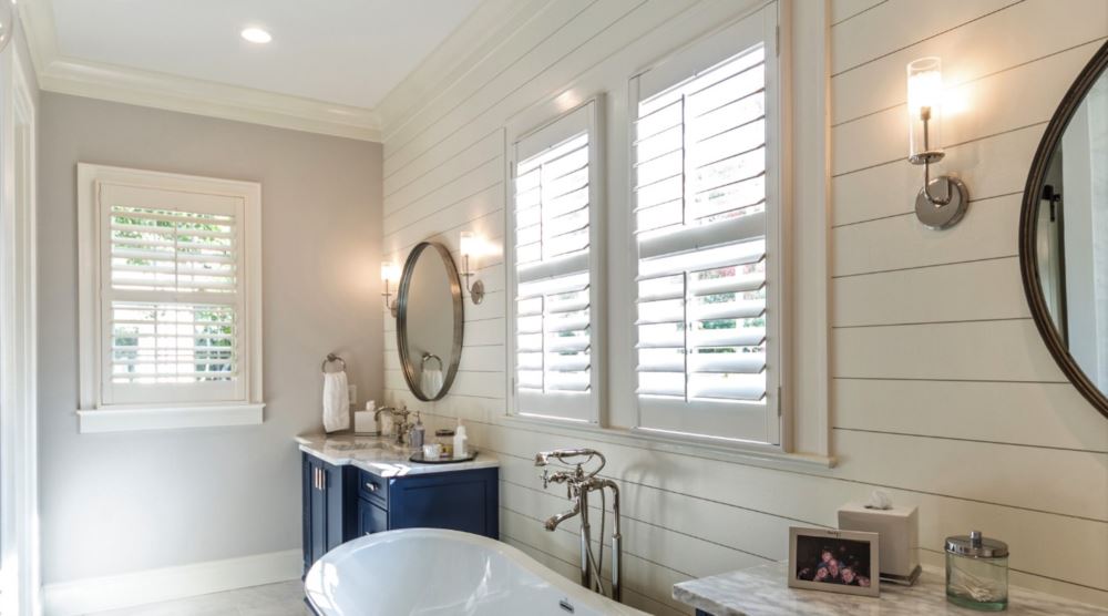 Riverside bathroom with white plantation shutters.
