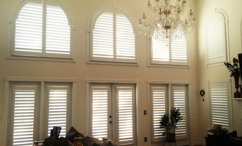 Great room in open concept Riverside home with plantation shutters on tall windows.