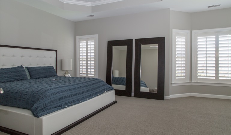 Polywood plantation shutters work well with minimalist design. White shutters in a minimalist bedroom in Riverside.