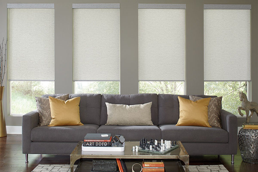 Motorized are the ultimate convenience when you need to effortlessly operate your window treatments. Light gray window shades on a row of windows in a gray living room