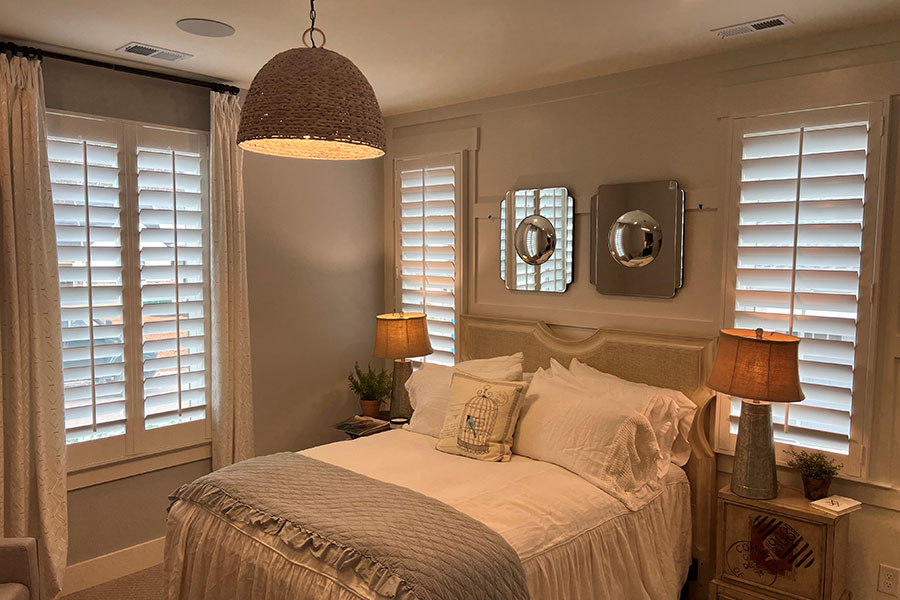 Use light-blocking interior shutters to help guests get a great night's sleep. White Polywood shutters in an elegant bedroom