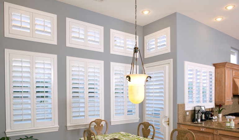 Shutters can solve both sun glare and heat loss problems. White plantation shutters in dining room