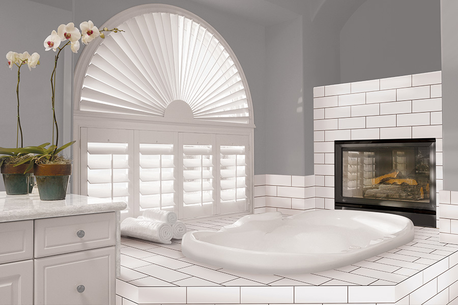 Explore our selection of window treatments for builders in Riverside to find the perfect ones for your next construction project. White Polywood shutters on an arched bathroom window