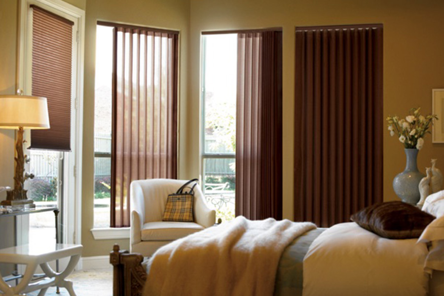 Choose durable and high-quality fabric or vinyl vertical blinds in Riverside. Maroon fabric vertical blinds inside a bedroom