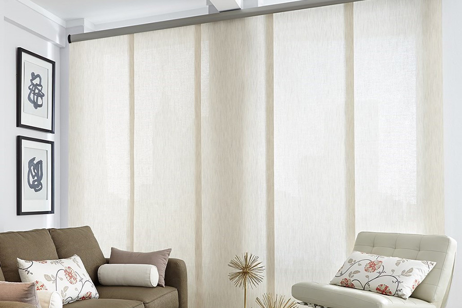 Find window treatments to complete any interior design among our extensive selection at Sunburst Shutters Riverside.  Long off-white window shades on a tall window in a modern living room