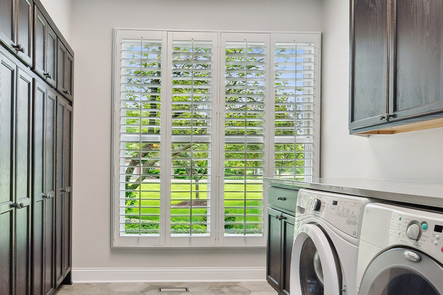 Find the perfect level of natural light for your Riverside laundry room with interior shutters. White Polywood shutters letting light through a laundry room window
