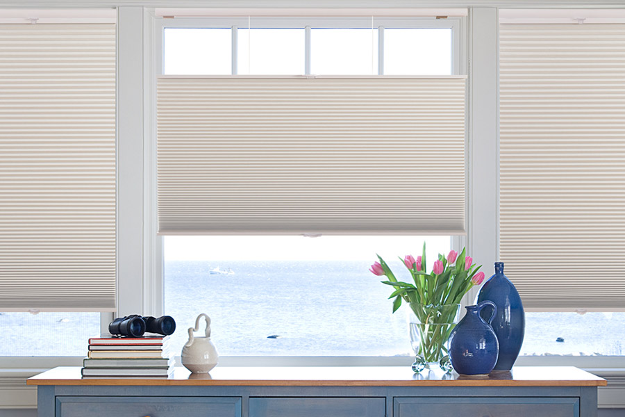 Cellular shades stay where they are placed -- good for casement windows. Blue chest of drawers inform of a casement window covered by neutral colored cellular shades