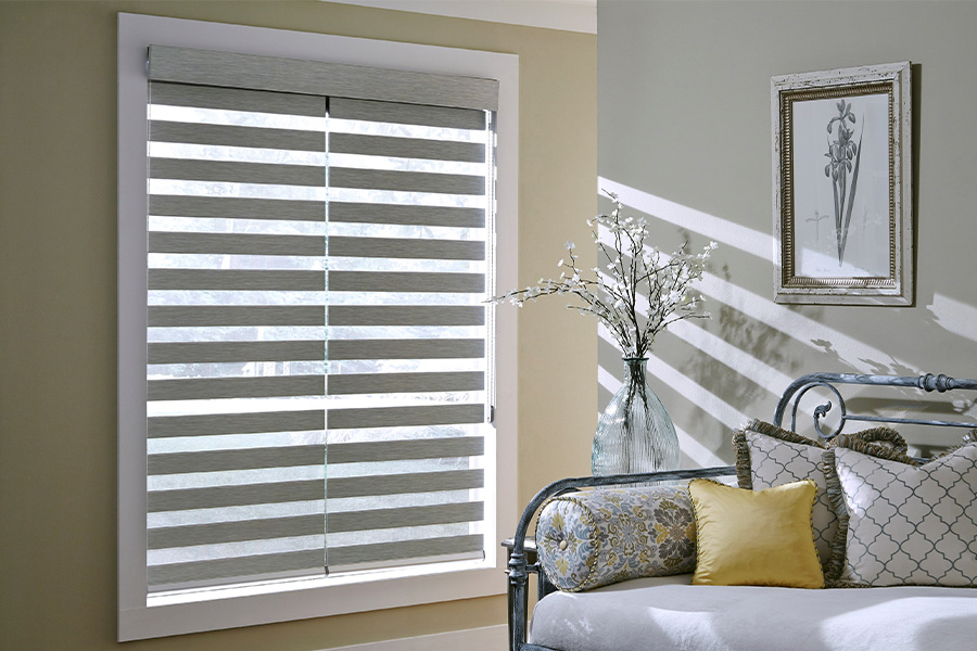 Find Practical and stylish window blinds for Riverside homes at Sunburst. Gray blinds on a large window next to a couch.