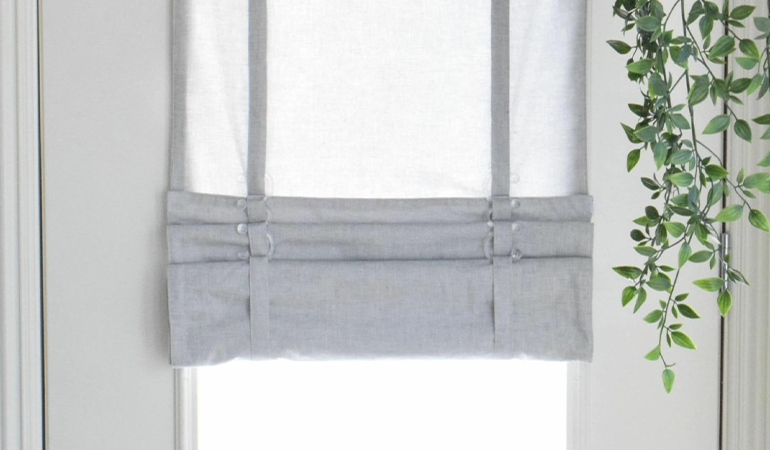 With a tiered tumble shade in Riverside, you can block sun glare all year round. Gray rolled tumble shade on a glass door