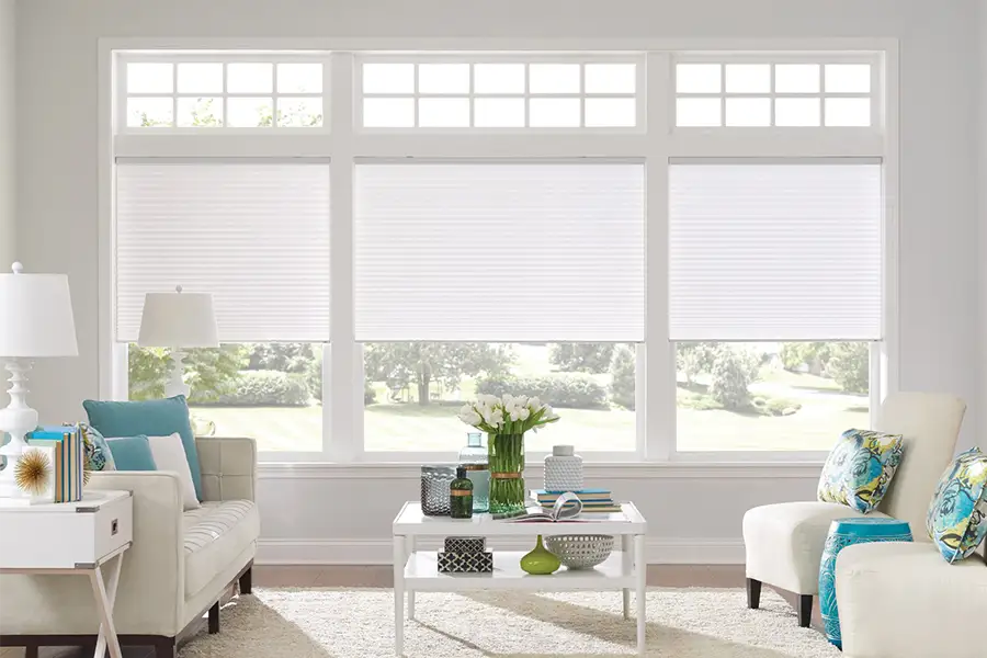 Insulating cellular shades can help keep cold air and hot UV rays from entering your Riverside home. White cellular shades on windows in a white living room