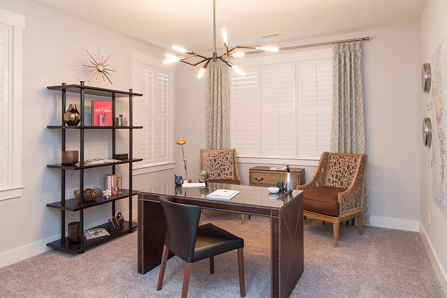 White window treatments help mismatched windows blend in with other neutral-colored decor and not stand out. White Polywood shutters on home office windows of different sizes